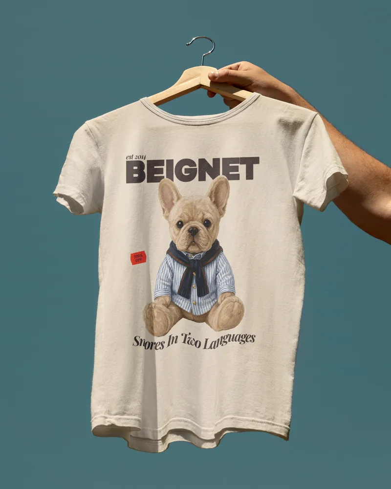 A cream tee printed with BEIGNET and a French Bulldog wearing a scarf.